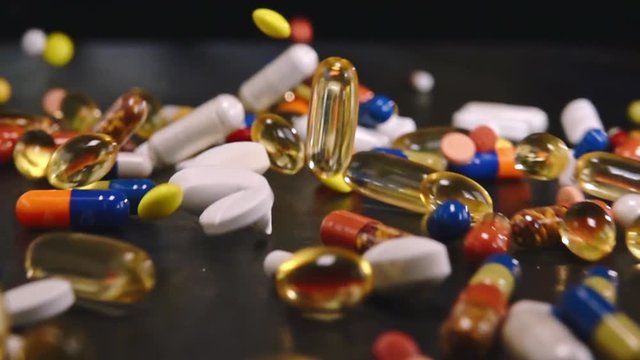 lots of random medical pills and coloured capsules falling down - authentic slow motion close up. Medical concept video 