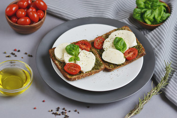 Mozzarella cheese with red tomatoes and basil leaves, pepper, olive oil, wooden desk, healthy food concept