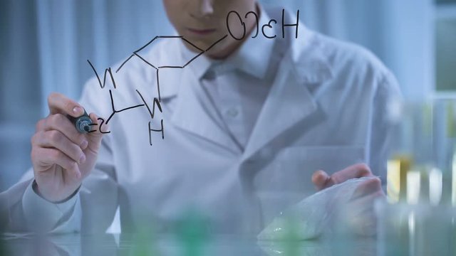Scientist holding sample of fertilizers, writing formula, theoretical research