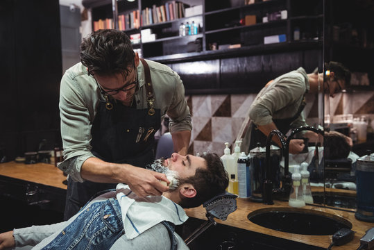 Barber applying cream on clients beard