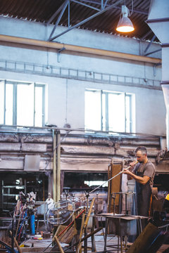 Glassblower shaping a glass on the blowpipe