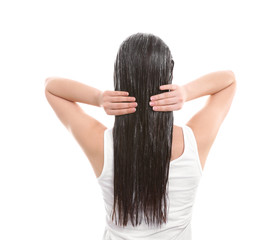 Young woman applying mask onto hair against white background