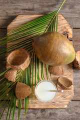 Composition with fresh green coconut and jar of milk on wooden table