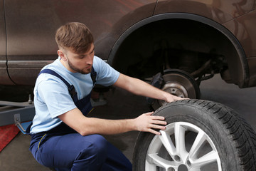 Mechanic changing car wheel in garage. Tire service