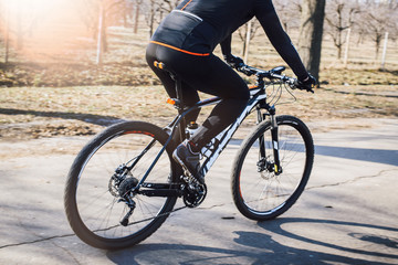 Fototapeta premium Professional cyclist in black uniform rides on his bicycle on the road in the park