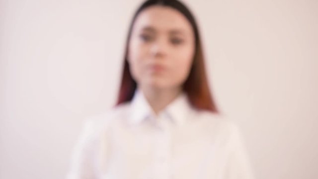 Young business woman on blurred white background in office. In field of sharpness is her hand. Woman presses the button on the glass screen. Makes a choice.Video with girl to add effects.