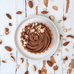 Chocolate tarts served with almond nuts on shabby white wooden surface