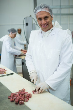 Butcher cutting meat into small pieces