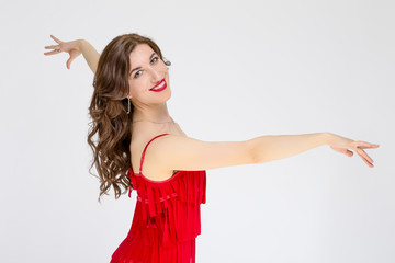 Ballroom Dances Project and Ideas. Portrait of Female Ballroom Dancer in Red Flowing Latin American Dress Against White. Demonstrating Rumba Dance.