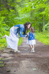 Fototapeta premium Family Ideas and Concepts. Happy Mother and Her Little Caucasian Daughter Posing with Kissing Expression Together In Green Summer Forest.