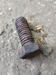 A rusted hex head cap screw bolt on concrete
