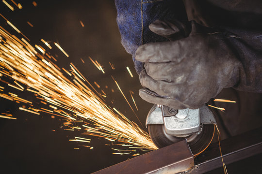 Close up of worker grinding metal with grinder