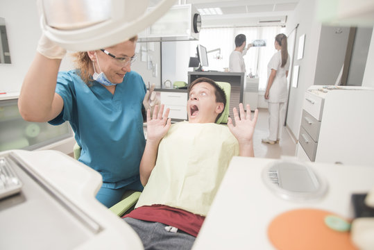 Young teenager is terrified at the dentist with the clinic at the background - oral hygiene health care concept