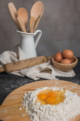 Eggs, dough, flour and rolling-pin on wooden table background. Preparation for making homemade ravioli pasta