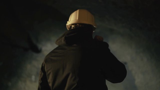 The speleologists with flashlight exploring the cave with fear