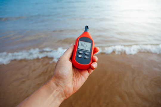 portable thermometer in hand measuring outdoor air temperature and humidity