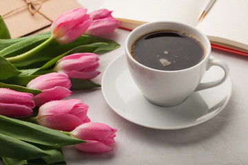 Woman working desk with coffee mug, notebook and spring tulip flowers top view in flat lay style