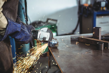 Welder cutting metal with electric tool in workshop
