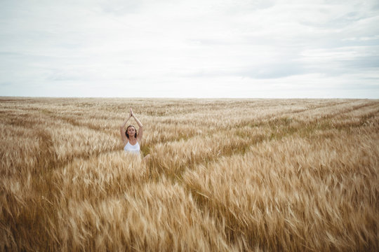 Woman with hands raised over head in prayer position in field