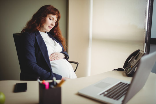 Pregnant businesswoman touching her belly