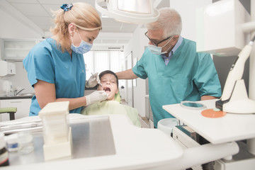 Boy with perfect teeth at the dentist doing check up with senior doctor attending - oral hygiene health care concept