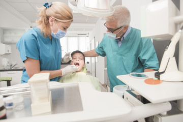 Obraz premium Boy with perfect teeth at the dentist doing check up with senior doctor attending - oral hygiene health care concept