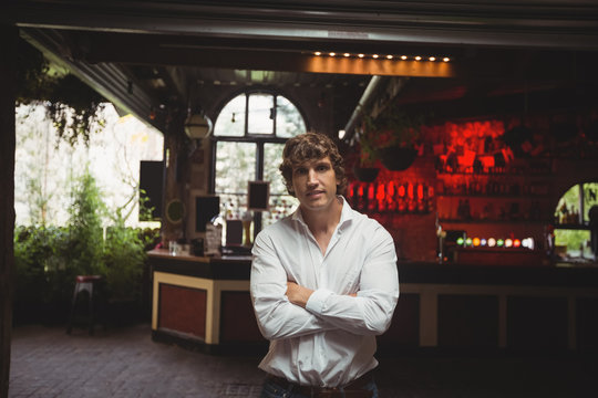 Man standing with arms crossed in bar