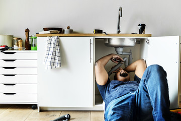 Plumber man fixing kitchen sink - Powered by Adobe