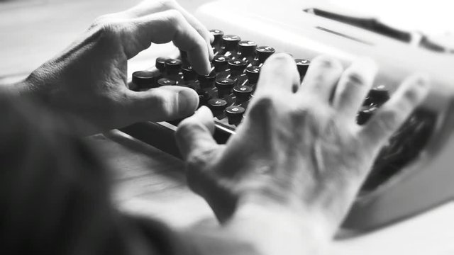  Hands typing a film script or a book on a vintage typewriter, 4k black and white video 
