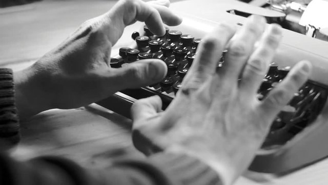  Hands typing a film script or a book on a vintage typewriter, 4k black and white video 