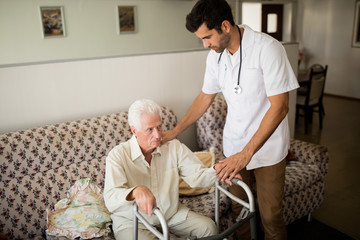 Nurse helping senior man to stand up