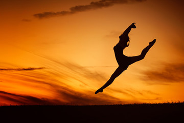 QUEBEC, QC - CANADA AUGUST 2011 : The silhouette of a ballerina jump in front of an orange sunset sky. She feels free as a bird.