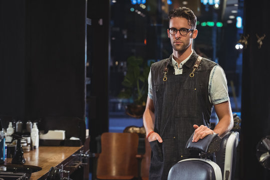 Portrait of male barber standing near chair