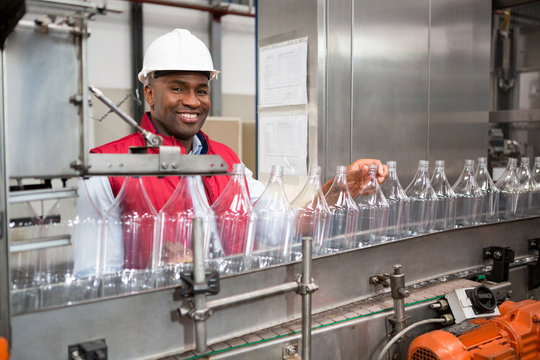 Confident male employee examining bottles in factory
