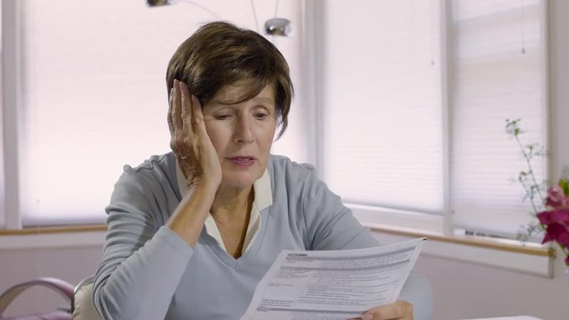 Older woman looking at bills, close up