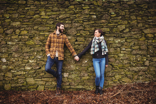 Couple leaning against stone wall