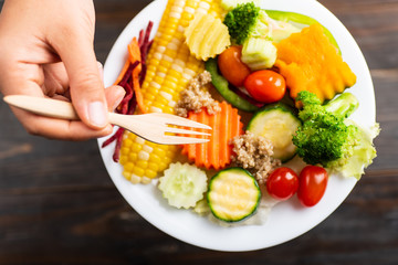 Hand holding fork and eating vegetables salad, healthy food, top view