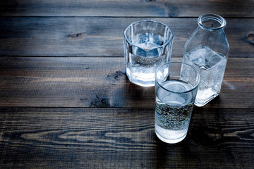 Drinks on the table. Pure water in jar and glasses on dark wooden background space for text