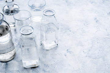 Drinks on the table. Pure water in jar and glasses on grey background space for text