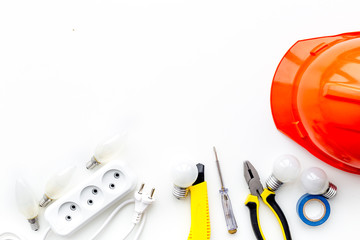 Electrician work concept. Hard hat, tools, socket outlet on white background top view