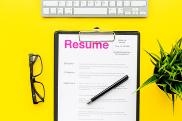 Empoyment concept. Resume on pad near pen and glasses on yellow background top view