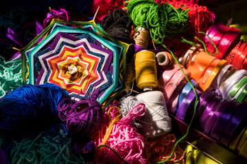 Multicolored balls of threads and tapes for needlework. Mandala woven from thread.