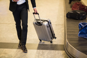 Businessman walking with luggage near baggage claim area