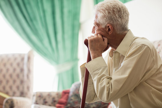 Thoughtful senior man sitting with a cane