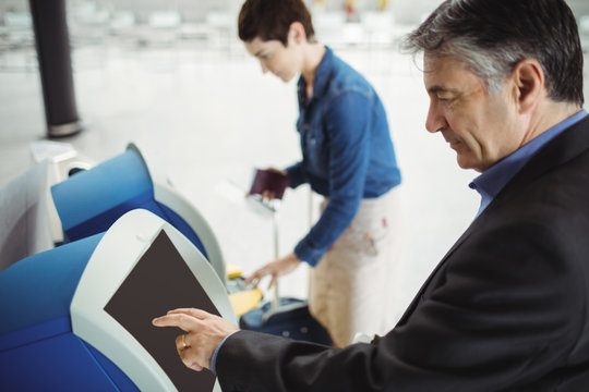 Businessman using self service check-in machine