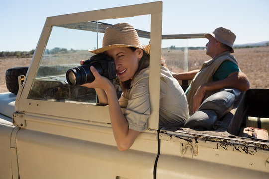 Woman photographing from camera while traveling in off road vehicle on field