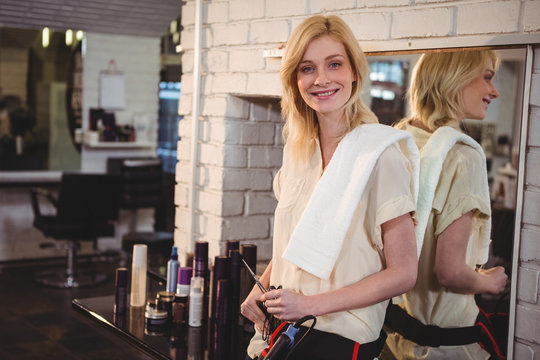 Smiling female hairdresser holding scissor in salon