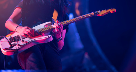 Guitarist playing his vintage guitar on stage. Guitar solo under blue, orange, purple lighting.