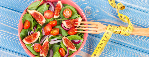 Fresh prepared fruit and vegetable salad, fork with tape measure, healthy lifestyle, slimming and nutrition concept