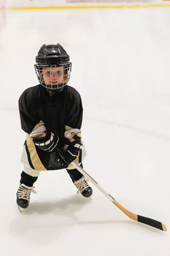 Adorable little kid 3 years-old plays hockey on ice wearing in full hockey equipment